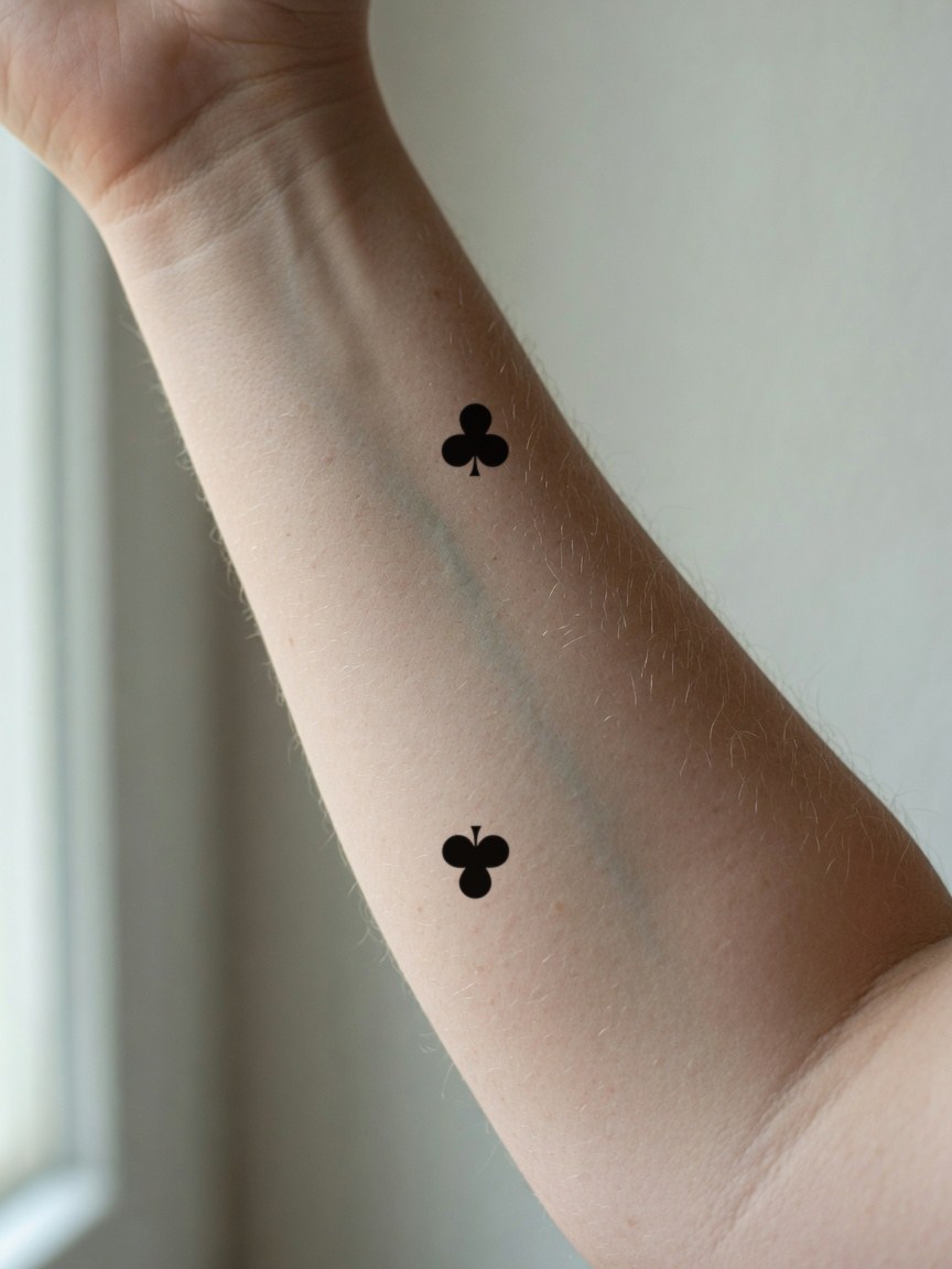 2 of Clubs pip tattoo on the inner forearm