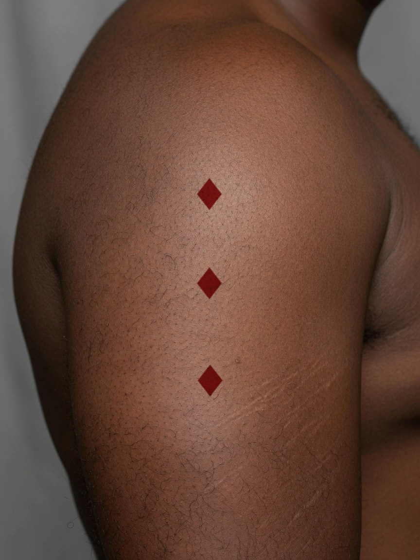 3 of Diamonds pip tattoo on the upper arm