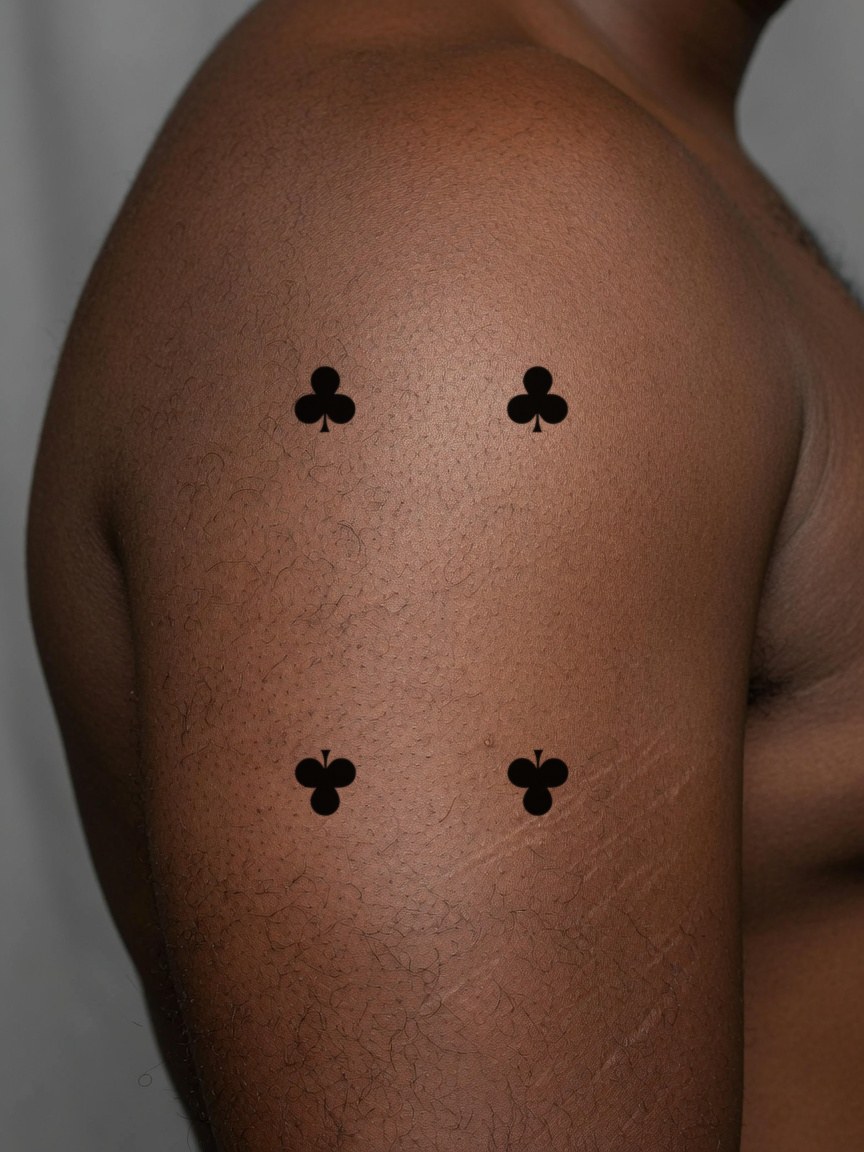 4 of Clubs pip tattoo on the upper arm