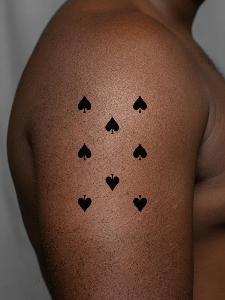 8 of Spades pip tattoo on the upper arm